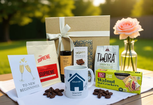 Gift basket with coffee, tea, snacks, and a mug on a table outdoors. Personalised Real Estate Settlement Gift Box