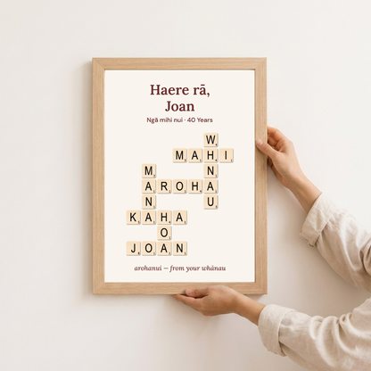 Personalised retirement gift in an oak frame held against a wall — te reo Māori "Haere rā" crossword design for Joan, 40 years