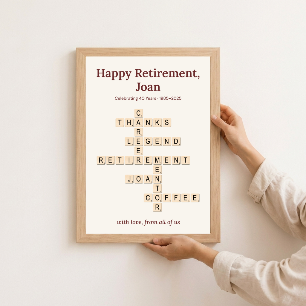 Personalised retirement gift in an oak frame held against a wall — "Happy Retirement, Joan" crossword keepsake, 1985–2025