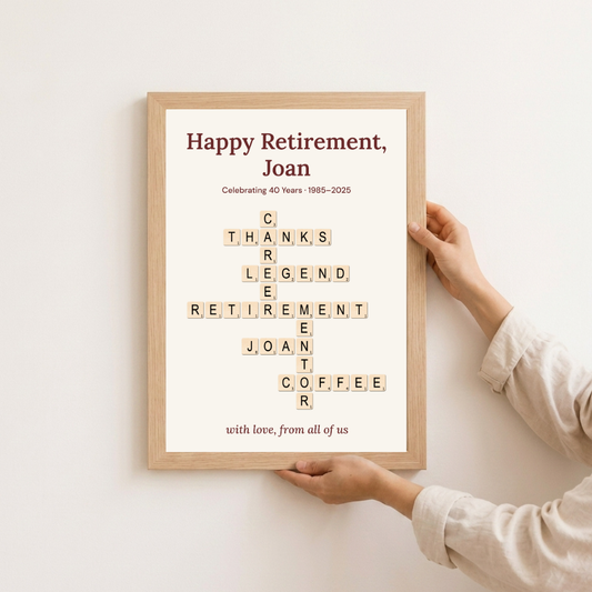 Personalised retirement gift in an oak frame held against a wall — "Happy Retirement, Joan" crossword keepsake, 1985–2025